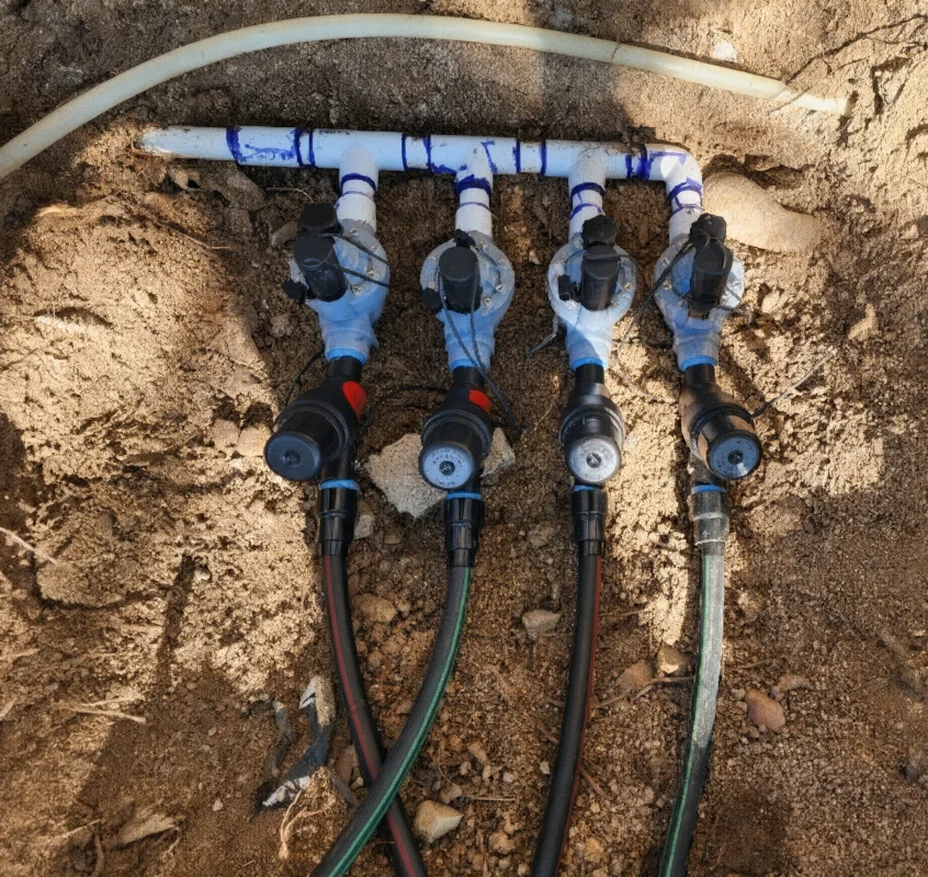 Part of the irrigation system is uncovered, showing the piping being installed in the backyard